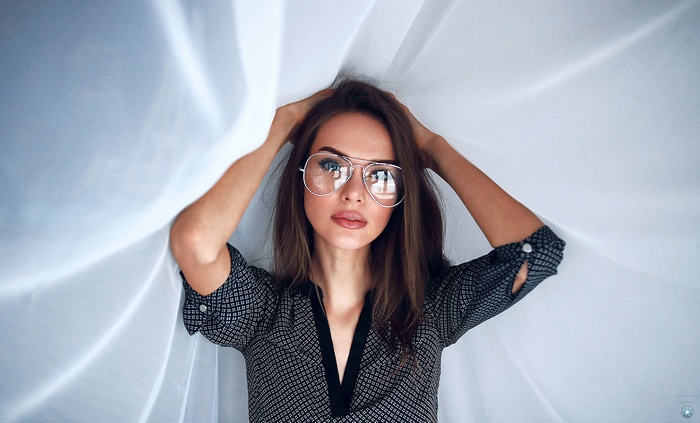 Woman with glasses and hands on head