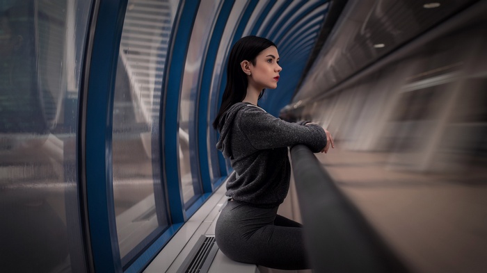 Woman in grey clothing sitting in a futuristic tunnel