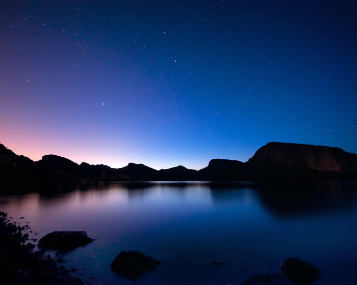 Night landscape with stars over a lake and mountains