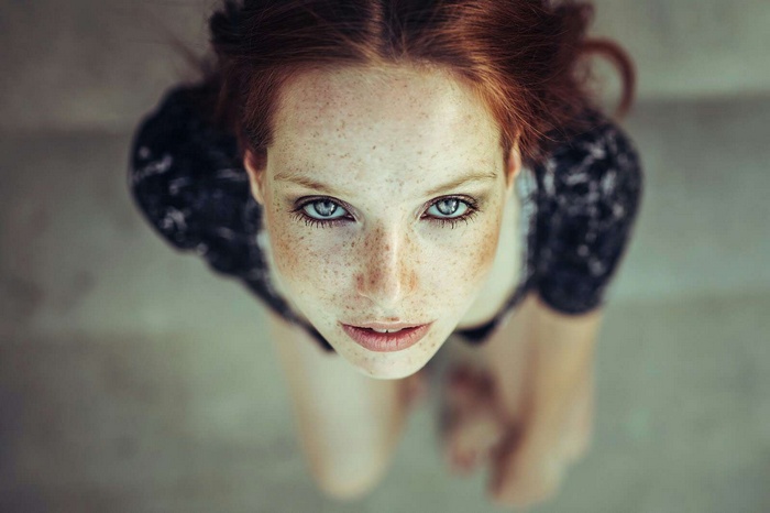 Woman with red hair and blue eyes looking up