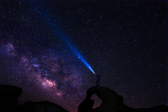 Person with flashlight under the Milky Way