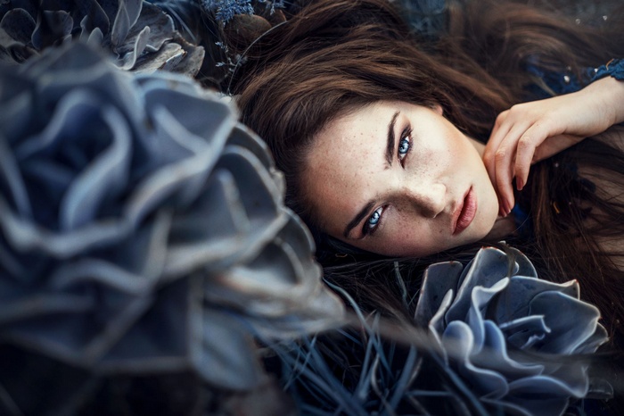 Woman with blue eyes and freckles lying down