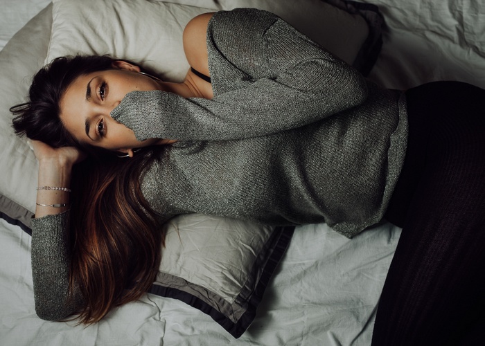 Woman in sweater lying on bed