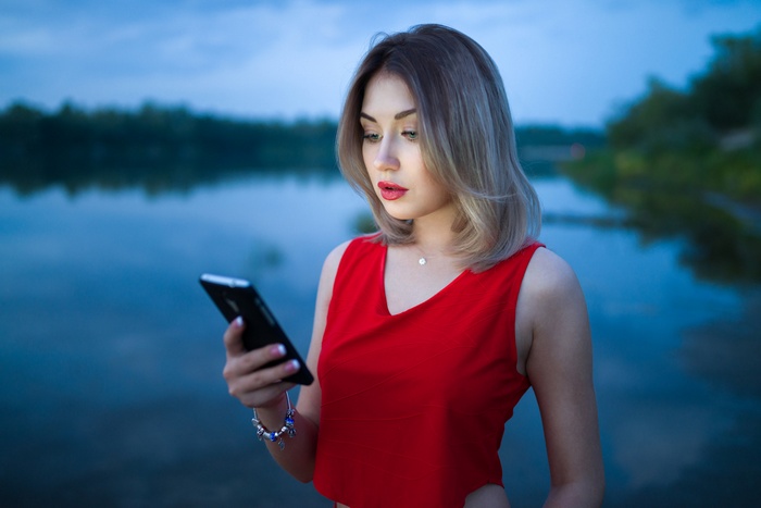 Woman in red top looking at cellphone outdoors