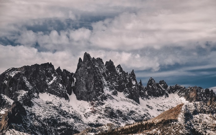 Snow-covered jagged mountains under a cloudy sky