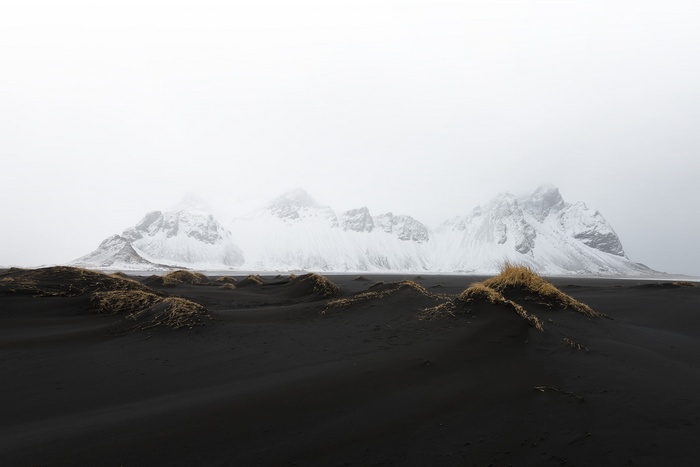 Snow-capped mountains over black sand dunes