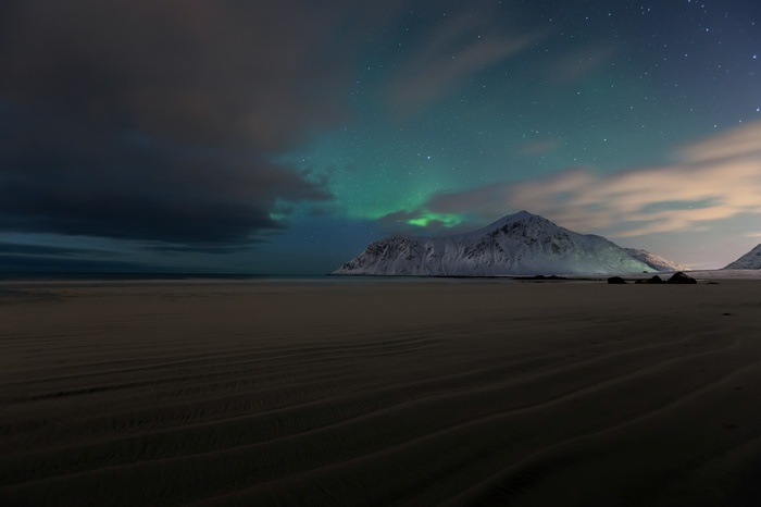 Aurora Borealis over snow-capped mountains and beach