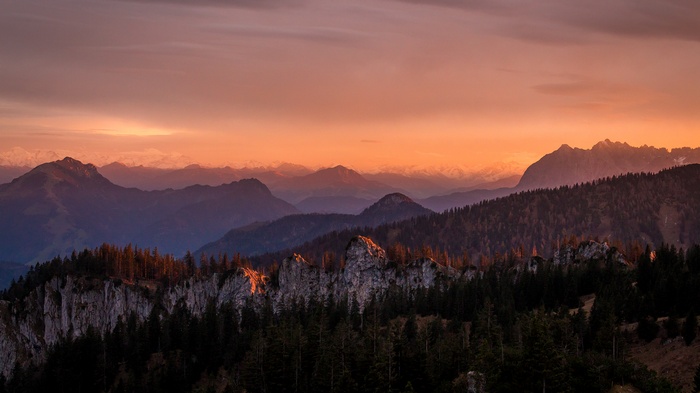 Mountain range at sunset with forest and clouds