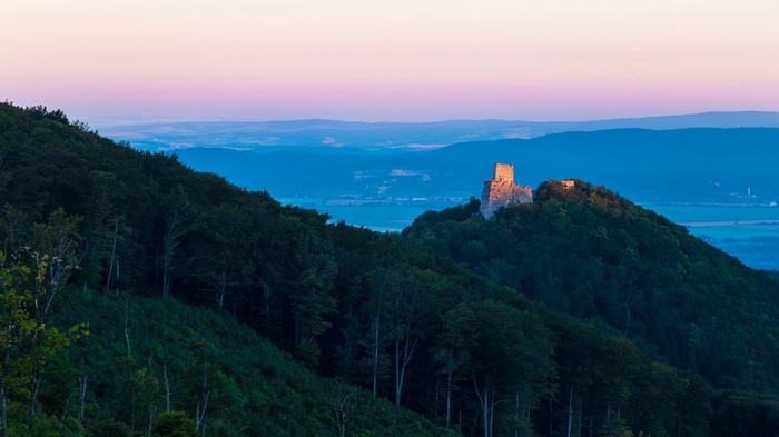 Castle ruins on a forested hill at sunrise in Slovakia