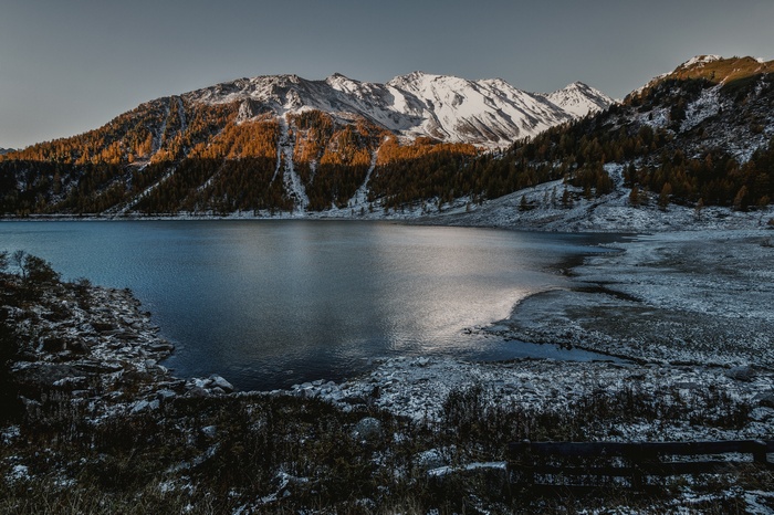 Snow-capped mountains overlooking a lake with autumn trees