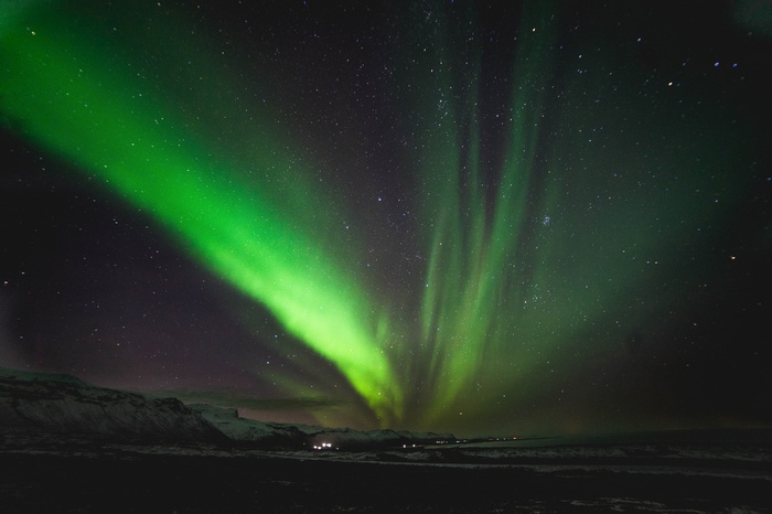 Green Aurora Borealis over Snowy Landscape