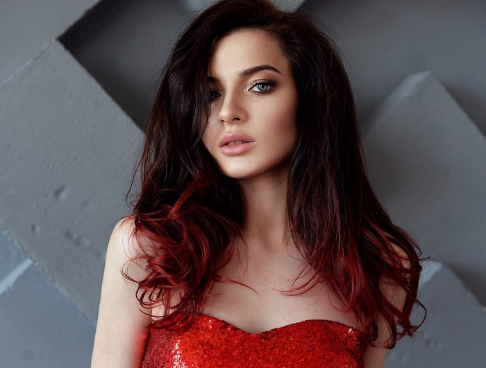 Woman with dark and red dyed hair in a red sequined dress