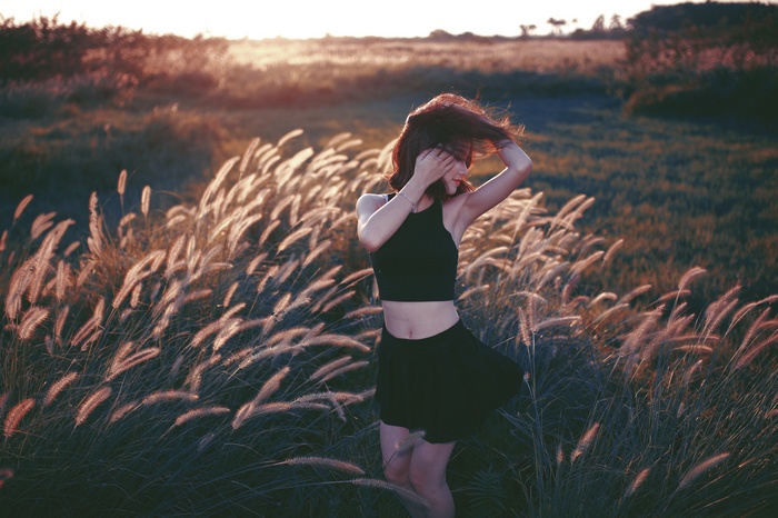 Woman in a black crop top and skirt in a field