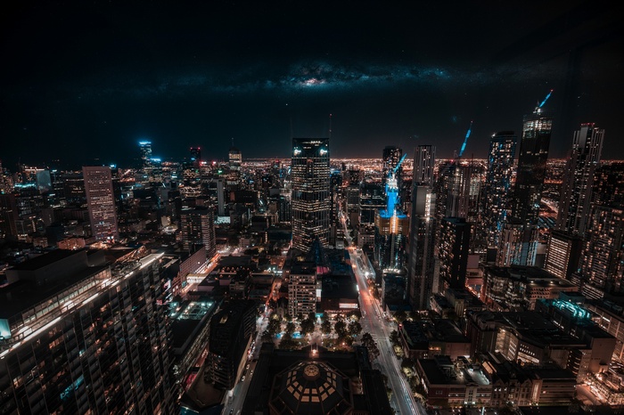 Aerial view of a city skyline at night with the Milky Way above