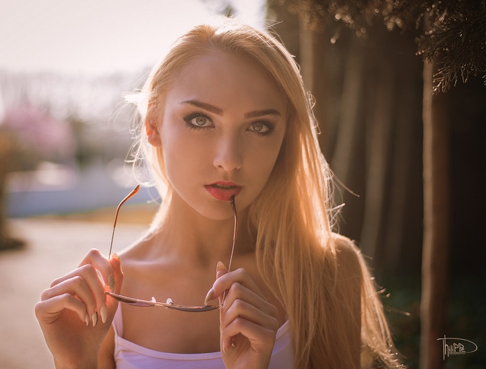 Woman with blonde hair holding glasses