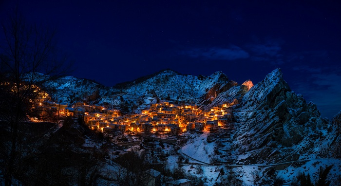 Village nestled in snowy mountains at night