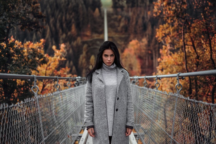 Woman standing on a suspension bridge in autumn