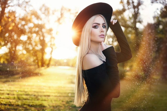 Woman with blonde hair wearing a black hat and dress outdoors