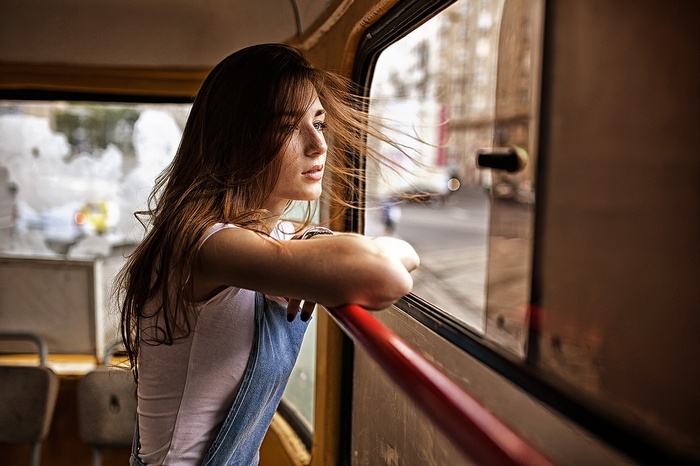 Woman in overalls looking out a window