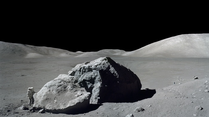 Astronaut on the Moon near a large rock
