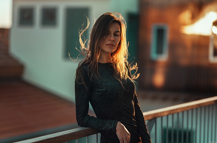 Woman in black dress with hair in face at sunset