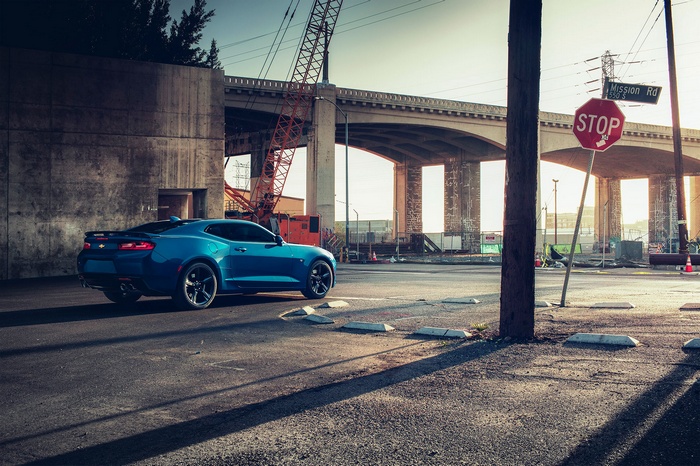 Blue Chevrolet Camaro at a street intersection with a stop sign