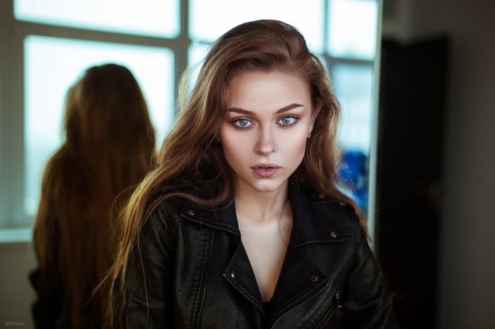 Woman in leather jacket reflected in mirror