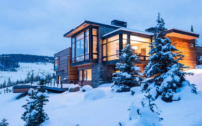 Modern house in snowy landscape with pine trees