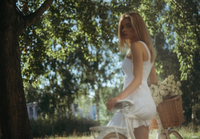 Woman in white dress with bicycle and flowers