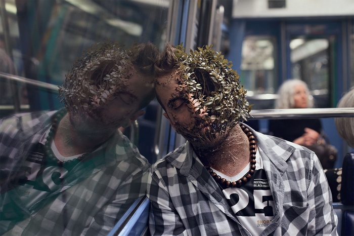 Man with plants on face in subway reflection