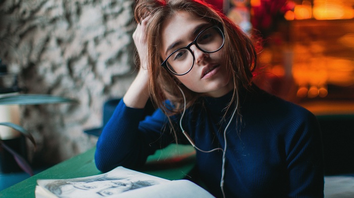 Woman with glasses wearing headphones and reading