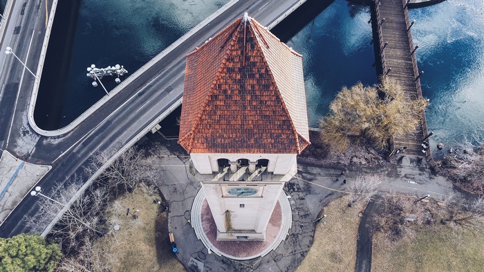 Tower with clock and red tiled roof over water with bridge