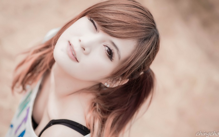 Asian woman with brown hair in ponytails winking