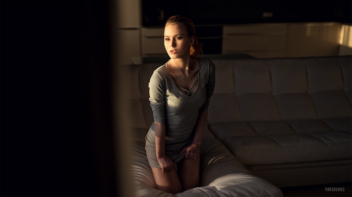 Woman in grey dress kneeling on a couch