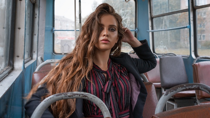Woman with wavy brown hair sitting in a bus