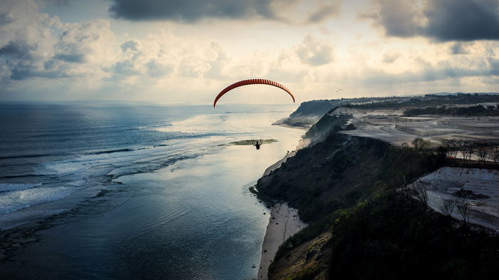 Paraglider over a cliff by the sea in Bali, Indonesia