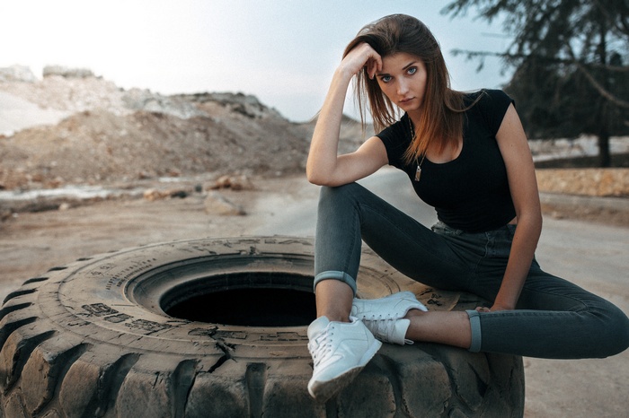 Woman in jeans and black t-shirt sitting on a tire