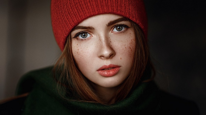 Portrait of a young woman with freckles wearing a red hat