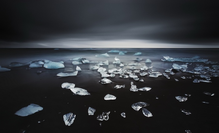 Ice chunks on a dark beach with a stormy sea and sky