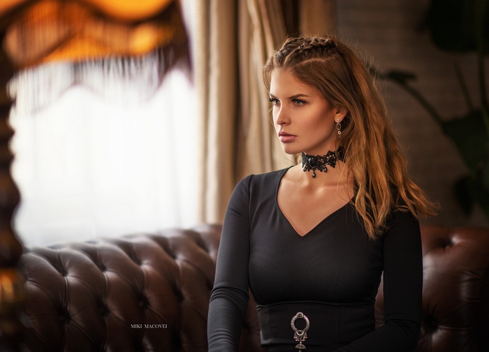 Woman with braided hair and choker sitting on a couch