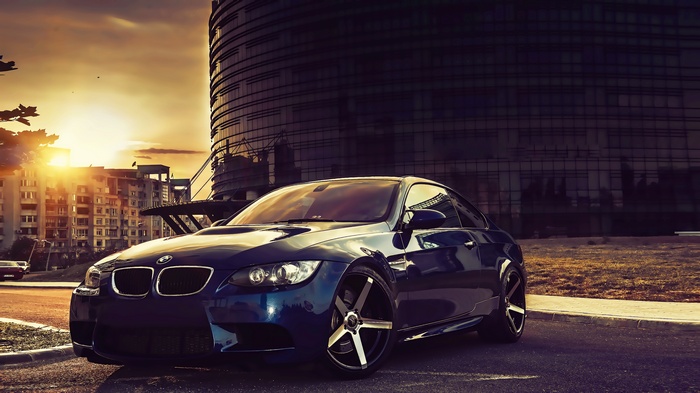 Blue BMW M3 Coupe parked in a city at sunset