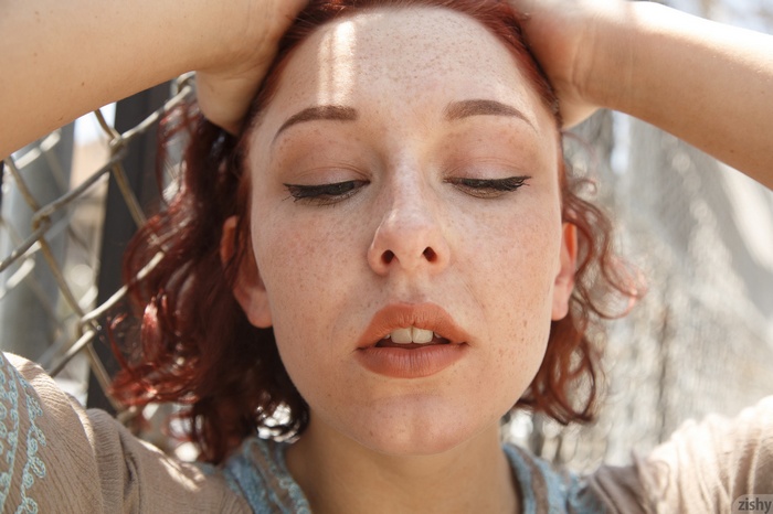 Woman with freckles and red hair, hands in hair