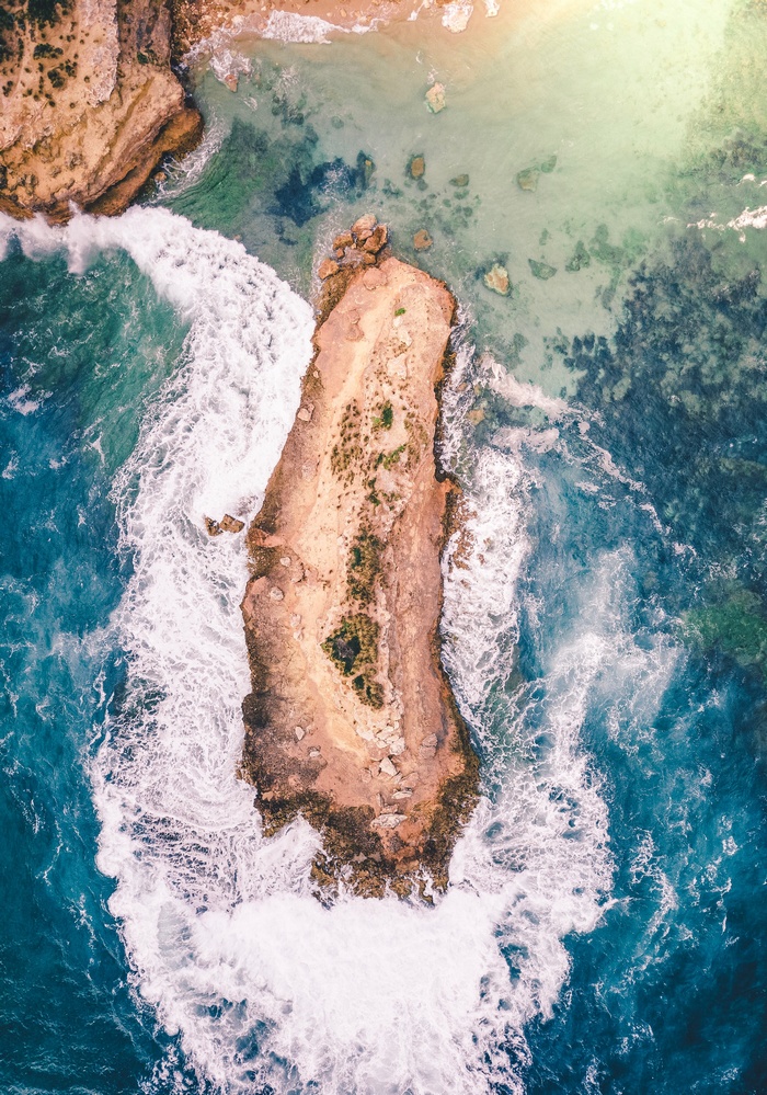 Aerial view of a rocky island surrounded by ocean waves