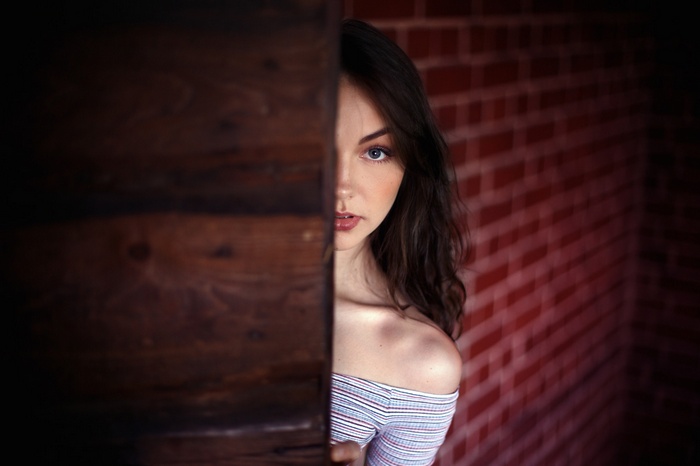 Woman peeking from behind a wooden surface