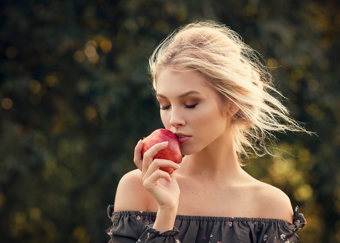 Woman with blonde hair holding an apple