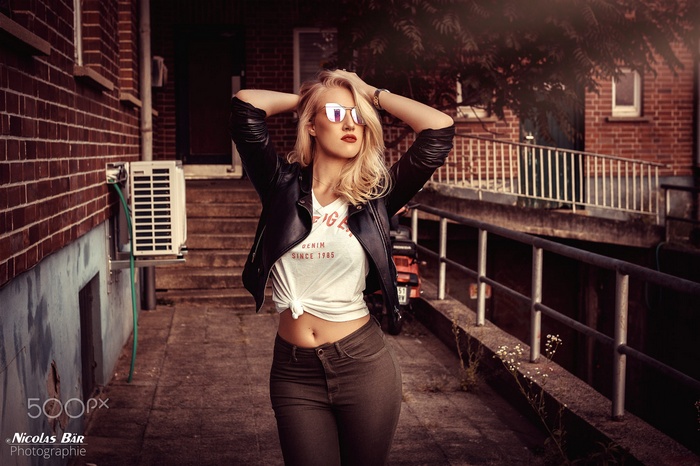 Woman in leather jacket and jeans with hands in hair