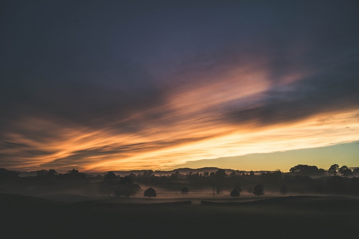 Misty landscape with dramatic sunset clouds over UK countryside