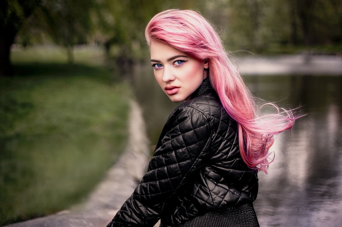 Woman with pink hair and blue eyes wearing a leather jacket outdoors