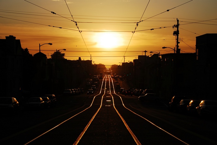 Sunset over a street with tram tracks and cars