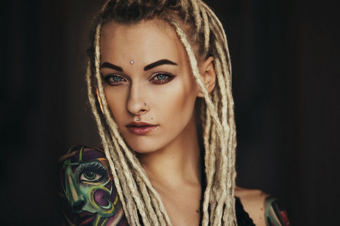 Woman with blonde dreadlocks and face tattoo
